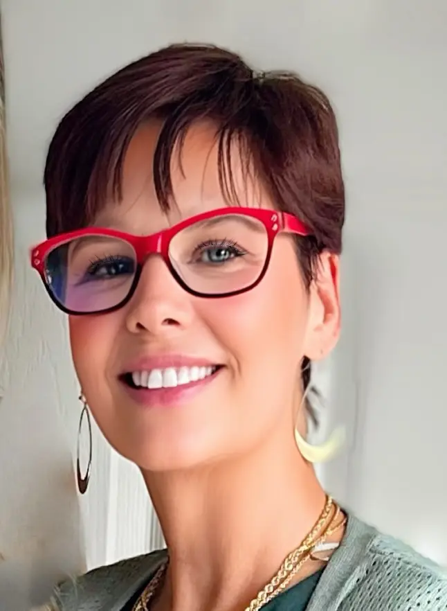 Kathy Photo 11.9.24 A woman with red glasses smiling for the camera.